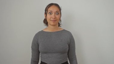 Şaşırmış ve korkmuş! Genç İspanyol kadın, şok olmuş ve korkmuş, izole edilmiş beyaz bir arka plan üzerinde inançsızlık içinde duruyor. Şaşırmış yüzü korku ve tarif edilemez bir sevinç karışımı gösteriyor..