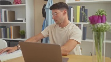 Modern ofis düzeninde dizüstü bilgisayarla çalışırken başı ağrıyan genç bir İspanyol..