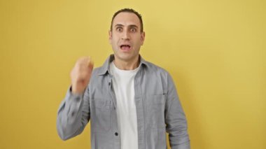 Gömlekli neşeli genç İspanyol bir adam, bir numaralı parmak hareketini sergiliyor, zekice bir başarı fikriyle ışıldıyor. Tek başına, canlı sarı bir duvarın karşısında duruyor..