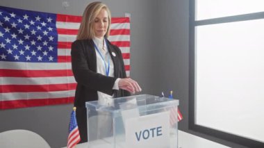 Amerikan bayrağıyla kapalı alanda seçim sürecini denetleyen sarışın bir kadın.