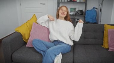 Kafkasyalı mutlu bir kadın. Oturma odasındaki kanepede dans ediyor ve müzik dinliyor..