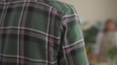 Kadın ve erkek canlı bir çiçekçide renkli çiçeklerle ve gür yeşilliklerle iç mekan iş sahnesini tasvir ederek etkileşime girerler..