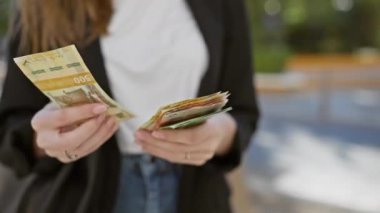 Bir kadın güneşli bir şehir caddesinde Norveçli kroner nakit para sayıyor, para, finans ve şehir hayatı sergiliyor..