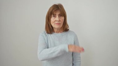 Hırslı orta yaşlı bir kadın, süveter giyiyor, beyaz bir arka planda yalnız duruyor, saldırgan bir bıçakla boğazını kesmekle tehdit ediyor..