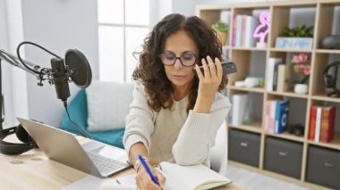 İspanyol kadın podcast mikrofon, dizüstü bilgisayar ve not defteri ile.