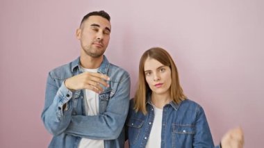 Sorunlu bir çift, kot gömlekli bir silah gibi parmaklarını keskin bir şekilde işaret ederek izole edilmiş pembe arka planda intihar jesti yapıyor. Güzel ve trajik bir ilişkide aşk ve depresyon