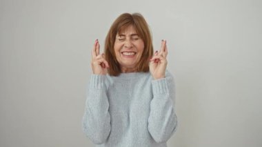 Umut dolu orta yaşlı bir kadın, gözleri kapalı, şans diliyor. İzole edilmiş beyaz arka planda neşeli, batıl inançlar