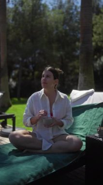 Dalgın genç bir kadın, yemyeşil yemyeşil bir otelin sakin bir bale merkezinde bir fincan kahveyle huzurlu bir sabah geçirir..