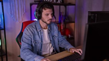 Karanlık bir odada oynayan yakışıklı sakallı bir adam. Renkli ışıklar ve modern kurulum konsantrasyonunu gösteriyor..