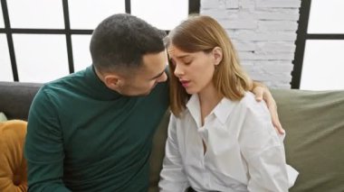 Sevecen erkek ve kadın rahat, modern bir oturma odasında kucaklaşıyorlar, rahat bir yuva ortamında sevgi ve beraberliği tasvir ediyorlar..