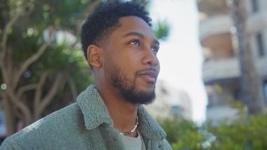 Düşünceli Afrikalı bir adam günlük giysiler içinde şehir bahçesinde huzurlu anların tadını çıkarıyor..