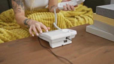 İçi rahat, dövmeli bir kadın eski moda bir telefonla şakacı bir şekilde konuşuyor.