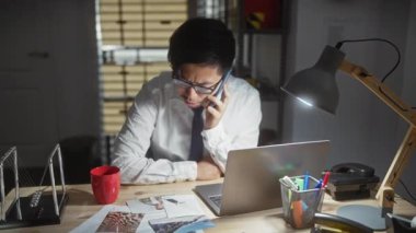 Akıllı telefon, dizüstü bilgisayar, bardak, kanıt, gözlük, lamba, dedektiflik, belge kullanarak geceleri görevde olan Asyalı bir adam.