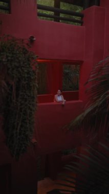 Genç bir kadın, tropikal bir tatil köyünde, verimli bir açık hava ortamında, mimari bir kırmızı oyukta dinleniyor..