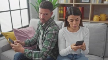 Bir erkek ve kadın, kapalı bir koltukta otururken akıllı telefonlarına odaklanırlar. Modern iletişimi ya da iletişimi kesmeyi önerirler..