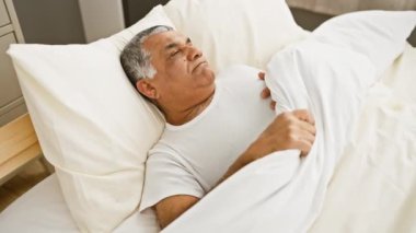 Olgun bir adam yatak odasında huzur içinde yatar. İçeride huzur ve huzur uyandırır..