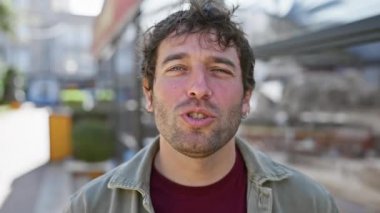 Sakallı, gülümseyen bir gencin şehir sokağında durduğu yakın plan..