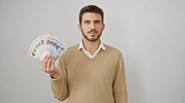 Neşeli genç İspanyol adam, neşeli bir şekilde parmaklarıyla kenarı işaret ederek, Güney Kore 'yi elinde tutuyor, beyaz bir arka planda izole edilmiş, para kazanıyor..
