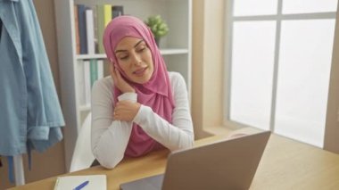 Neşeli genç İspanyol kadın başörtüsü takıyor, rahat evindeki bilgisayarına dişlek bir gülümseme sergiliyor, kendinden emin sevinçle dolup taşıyor..