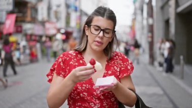 Osaka 'nın ünlü dotonbori caddesinde çilekli Japon mochi' sinden hoşlanan, gözlüklü göz kamaştırıcı İspanyol kız.