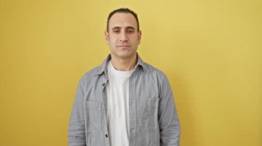 Neşeli, genç, İspanyol bir adam eliyle gözlerini kapayıp bir sürprizle alay ediyor. Parlak sarı bir duvarın önünde dikiliyordu. Çekici gülüşü gömleğinin yakasından dışarı bakıyordu..