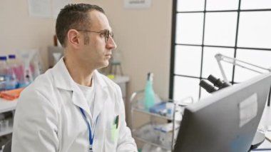 Laboratuvar önlüklü İspanyol bir adam laboratuvar ortamında bilgisayardaki verileri analiz ediyor..