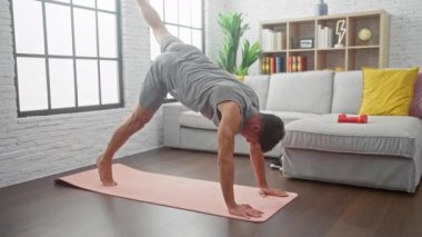 Genç bir İspanyol, yoğun bir dağ tırmanışçısı egzersizi yapıyor. Modern, parlak bir oturma odasında pembe bir yoga minderinin üzerinde..