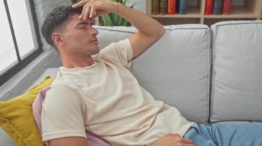 Yakışıklı, genç, İspanyol bir adam. İyi dekore edilmiş bir evin içindeki kanepede dalgın dalgın yatıyor..