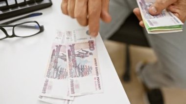 Ofiste orta yaşlı bir adam elinde Rus rublesi ve klavye tutuyor..