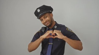 Polis üniforması içindeki neşeli Afro-Amerikalı adam aşkı sergiliyor, izole beyaz arka planda elleri olan bir kalp yapıyor. romantik kavram!