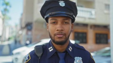 Gülümseyen Afro-Amerikan polisi şehir ortamında üniforma giyiyor.