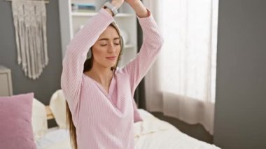 Bir kadın yatak odasında dinleniyor, dinleniyor ve meditasyon yapıyor. Huzurlu bir evde kulaklıklarla müzik dinliyor..