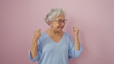 Gözlüklü neşeli, kır saçlı, son sınıf öğrencisi, kazanan duruş ve başarı abidesi! Mutlu, heyecanlı çığlık pembe izole arka planda.