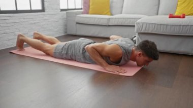 Modern bir apartman dairesinde yoga yapan İspanyol bir adam fiziksel kondisyon ve dikkatli meditasyona odaklanıyor..