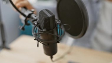 Kulaklıklı İspanyol adam modern bir podcast stüdyosunda mikrofona konuşuyor..