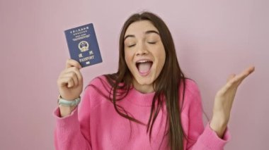 Neşeli genç İspanyol kadın zaferi sevinçle kutluyor, Hong Kong pasaportu elde etme başarısı! Esmer genç kendinden geçmiş bir şekilde izole edilmiş pembe duvar arkaplanından el kaldırıyor..