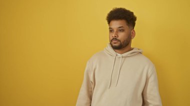 Sarı arka planda sıradan bir kapüşonlu yakışıklı Afro-Amerikan bir adamın portresi.