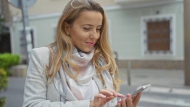 Kendine güveni tam bir kadın. Şehir sokağında dikilirken akıllı telefondan mesaj atıyor.