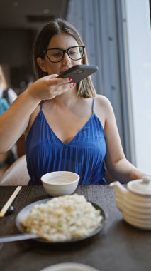 Lezzetli bir yemek, gözlüklü güzel bir İspanyol kadın modern bir restoranda yemek fotoğrafı çekiyor.