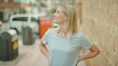 Young blonde woman smiling confident looking to the side at street