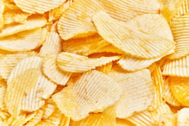Patates cipsleri üst üste yığılıp, kıvrılmış dokularının ve altın renginin detaylarını yakalıyor..