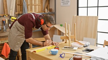 İyi organize edilmiş bir marangozluk atölyesinde alet kullanan yakışıklı bir zanaatkar..