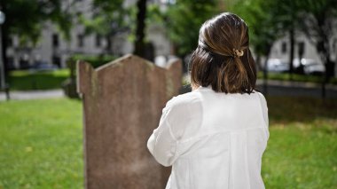 Güzel, genç, İspanyol bir kadın mezarlıkta dua ediyor ve yas tutuyor.