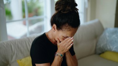 Middle age hispanic woman suffering for domestic violence with bruise on eyes crying at home