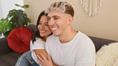 Mutlu bir çift, sıcak bir oturma odasında kanepede sarılıyor, sevgi ve birliktelik yayıyor..