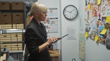 Sarışın bir kadın dedektif, polis merkezinde kanıt analizi yapıyor..