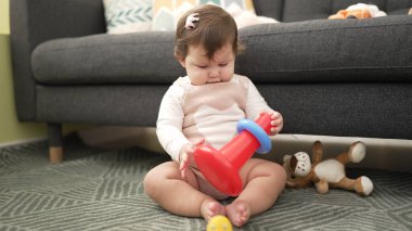 Adorable toddler sitting on floor playing with hoops at home