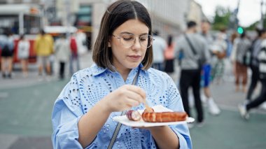 Genç ve güzel İspanyol kadın Viyana sokaklarında Ksekrainer sosisi yiyor. 