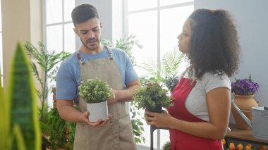 Çiçekçi erkek ve kadın çiçekçiler çiçek dükkanında çiçek düzenliyorlar. Takım çalışmasını ve küçük işletmeleri temsil ediyorlar..