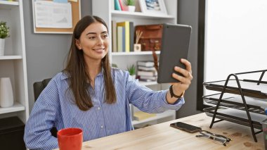 Genç bir İspanyol kadın modern ofis ortamında selfie çekiyor, göz alıcı güzellik ve profesyonellik..